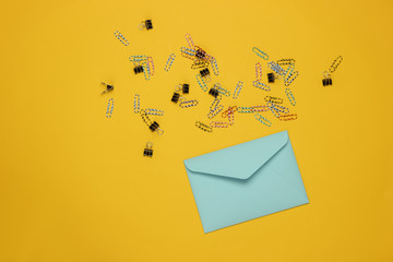 Envelope and paper clips on a yellow background. Top view