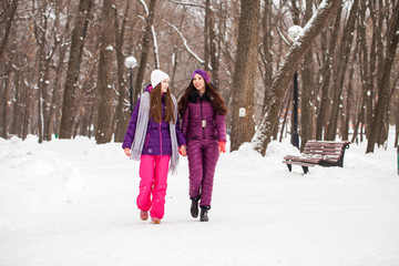 Fototapeta na wymiar Two happy beautiful girlfriends walk in the winter in a city park