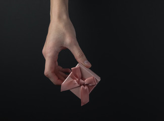 Female hand hold gift box with a bow on a black background. Black friday concept