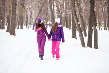 Fototapeta na wymiar Two happy beautiful girlfriends walk in the winter in a city park