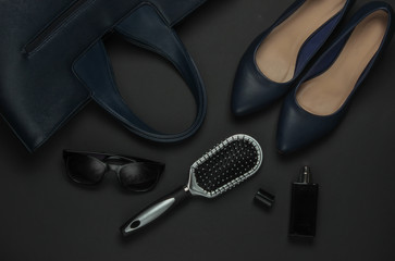 Women's accessories on a black background. High heel shoes, leather bag, comb, sunglasses, perfume bottle. Top view