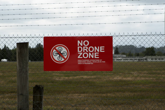 No Drone Zone warning sign on chainlink and barbed wire fence.