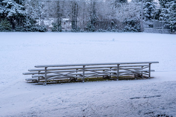 Empty snow-covered bleachers in snowy playfield