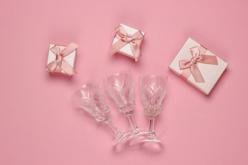 Retro style faceted crystal wine glasses and gift boxes on a pink background. Christmas concept. Top view