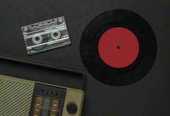 Retro media. Radio receiver, vinyl record, audio cassette on a black background. Top view.