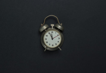 Retro alarm clock on black background. 11:55 am. New Year. Top view