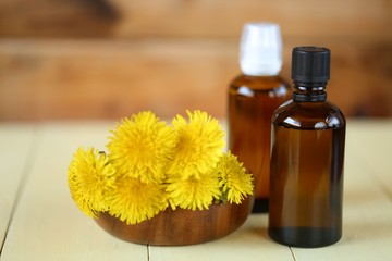 Dandelion tincture. Herbal tincture. Medicinal herbs.  Medicinal tincture in brown glass bottles and dandelion flowers on a  wooden background.infusion of healing herbs. 