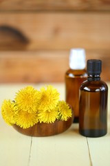 Dandelion tincture. Herbal tincture. Medicinal herbs.  Medicinal tincture in brown glass bottles and dandelion flowers on a  wooden background.infusion of healing herbs. Homeopathy