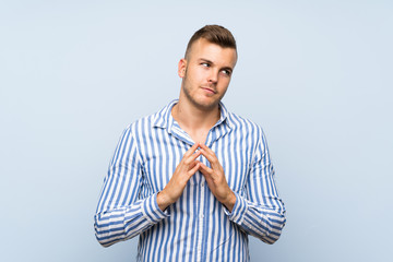 Young handsome blonde man over isolated blue background scheming something