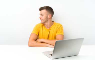 Young blonde man in a table with a laptop looking to the side