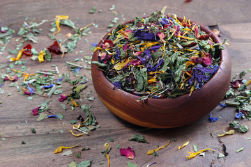 medicinal herbs in a wooden bowl. dry mint, hibiscus flowers, calendula petals, forest mallow...
