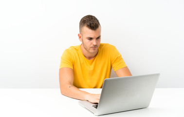 Young blonde man in a table with a laptop