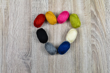 Heart of colored skeins of yarn for knitting on a wooden background.