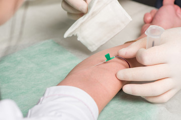 Hand in latex medical gloves perform vein puncture in area of ulnar bend of patient 's hand