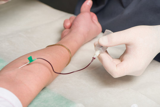 Hands in medical gloves make vein puncture in area of ulnar bend of patient 's hand