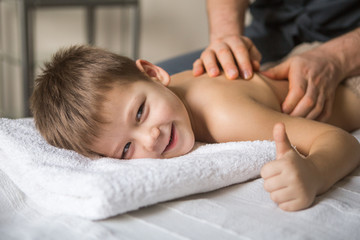 Boy toddler relaxes from a therapeutic massage. Physiotherapist working with patient in clinic to...