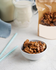A handful of walnuts in close-up, next to a package of nuts with space for text and logo. 