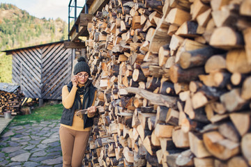 nerd girl in eyes stands on street near stack of firewood and reads book.