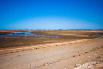 The coastal strip (coastline, beach) at low tide with border between leaving water and a beach. A wide desert area with wet sand. Makey, Queensland, Australia.