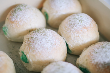 Homemade sweet buns with powdered sugar. Sweet breakfast.Close up view of baker is working.Tasty sweet buns with sweetened condensed milk, Thai tea custard on plate and icing sugar