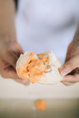 human pick homemade bun with powdered sugar. Sweet breakfast.Close up view of baker is working.Tasty sweet buns with sweetened condensed milk, Thai tea custard on plate and icing sugar