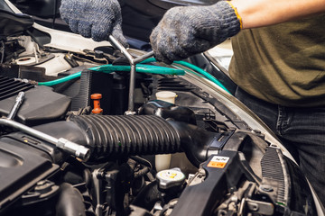 Fototapeta na wymiar Mechanic hands working holding a wrench and socket on the engine in car at garage .service and maintenance concept . selective focus