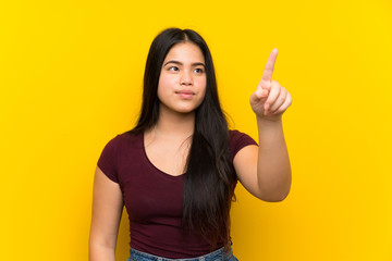 Young teenager Asian girl over isolated yellow background touching on transparent screen