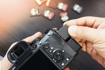 Photographer hand open the memory card slot cover and Insert memory card to camera slot at studio. selective focus