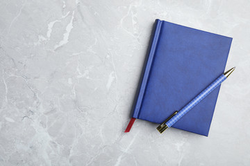 Stylish notebook and pen on marble table, top view. Space for text