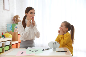 Speech therapist working with little girl in office