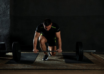 Fototapeta na wymiar Strong man lifting barbell in modern gym