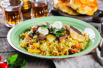 National Traditional Uzbek pilaf with meat and rice on a wooden table. Oriental cuisine concept. Close-up image