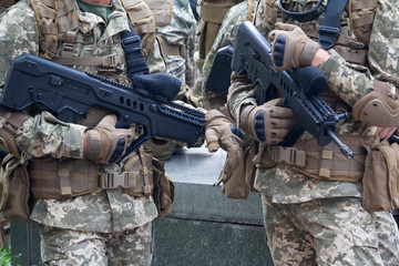 Automatic rifles in the hands of soldiers close up. Weaponry