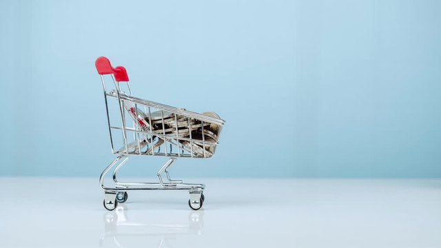 Shopping cart with coin on blue background. 4k Stop motion.