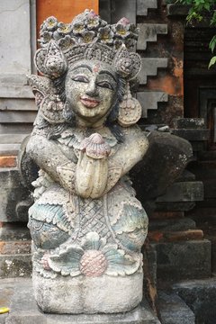 Ancient carved stone guardian statue with painted face at a temple in Bali Indonesia