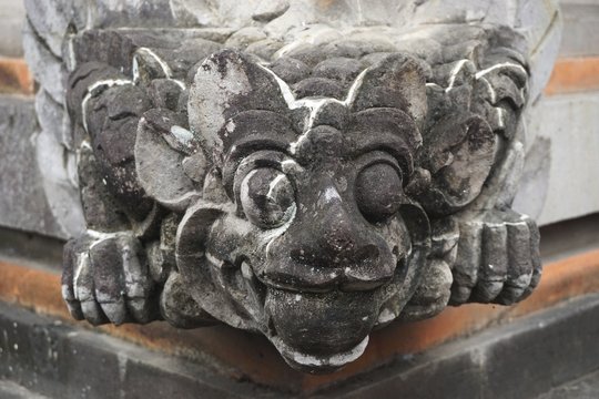 Smiling stone gargoyle at a temple in Bali Indonesia