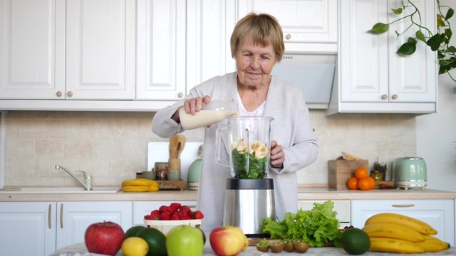Senior Woman Preparing Vegan Organic Smoothie On Kitchen. Healthy Lifestyle.
