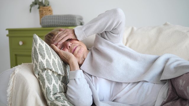 Old Woman Suffering From Headache Lying On Sofa