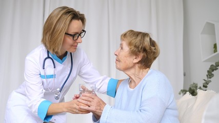 Doctor Nursing A Senior Woman By Giving A Glass Of Water