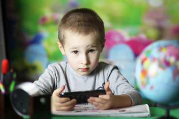 Child with a gadget. Little serious boy. Four year old child with a smart look.