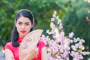 Portrait beautiful Asian girl wearing Cheongsam red dress hold a fan