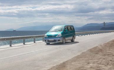Minivan moves on the highway along the sea