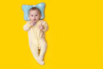 seven month old baby laughs lying on a yellow background