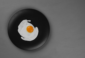 English breakfast fried eggs and bacon on black plate. top view