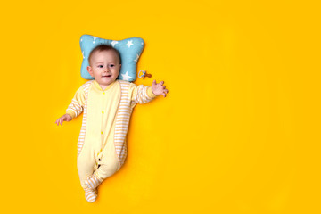 seven-month-old baby sucks a dummy pacifier on a yellow background