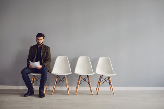 Worker awaits interview sitting on a chair in the room.
