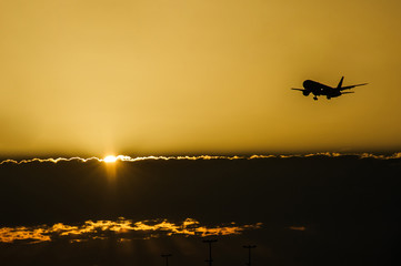 Jet plane landing in sunrise time in front of dramatic sky.