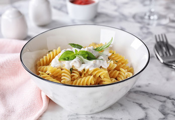 Delicious pasta with sauce served on white marble table