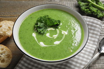 Tasty kale soup with cream on wooden table
