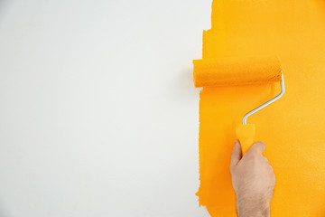 Man painting white wall with yellow dye, closeup. Interior renovation
